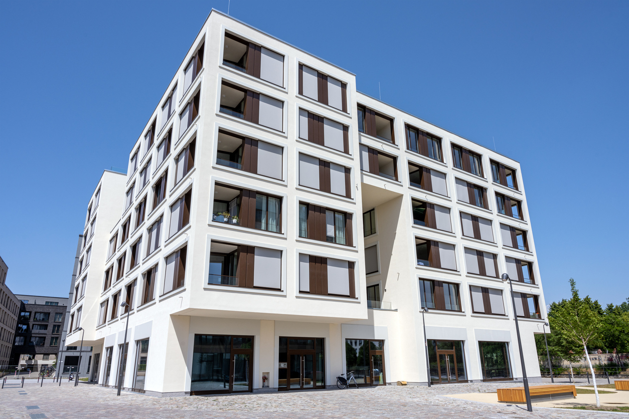 Bâtiment tertiaire blanc de plusieurs niveaux avec vitrines en rez-de-chaussée, façades enduites après isolation