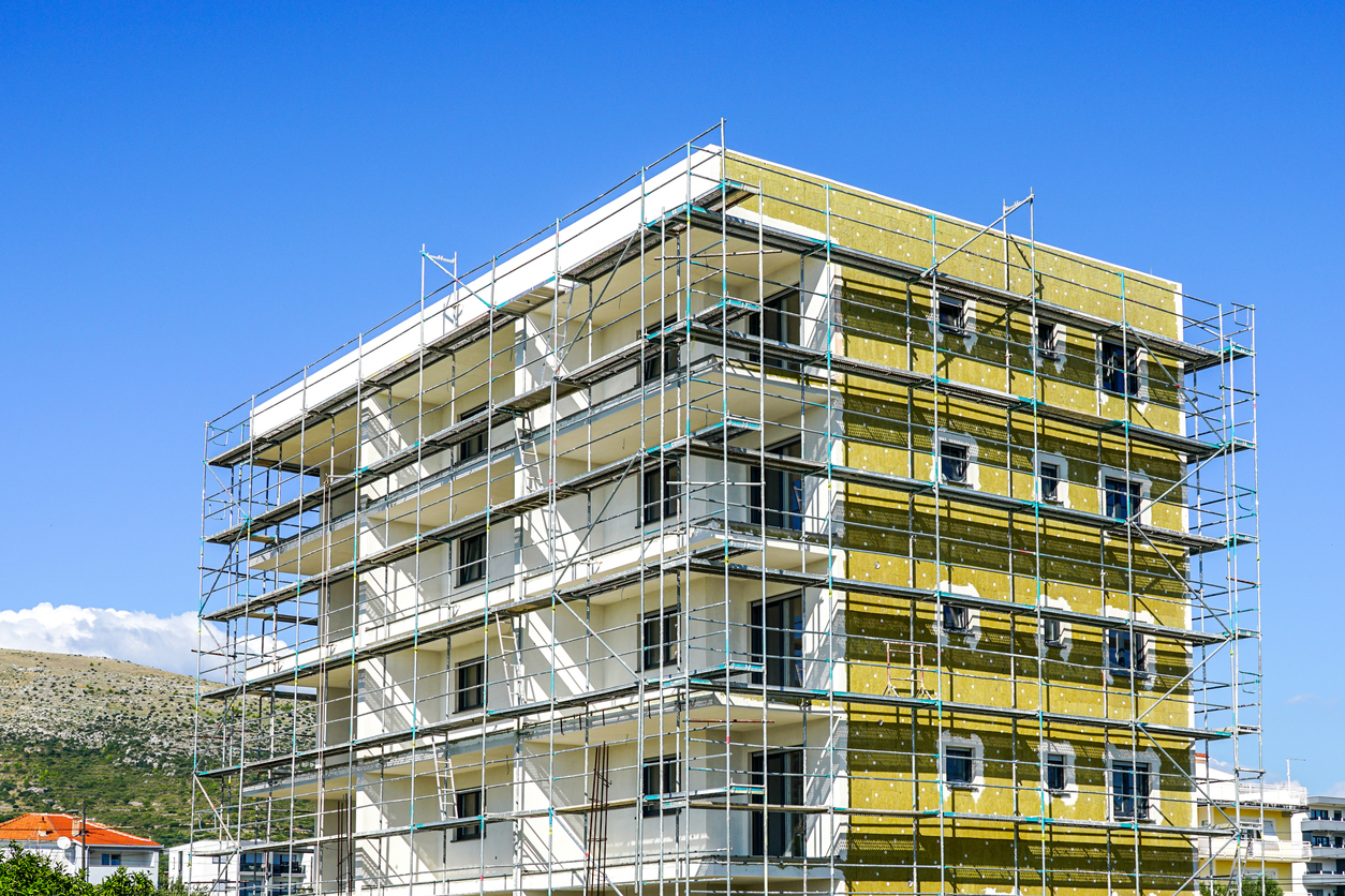 Façade de bâtiment en cours d'isolation extérieure, laine minérale posée sur plusieurs niveaux
