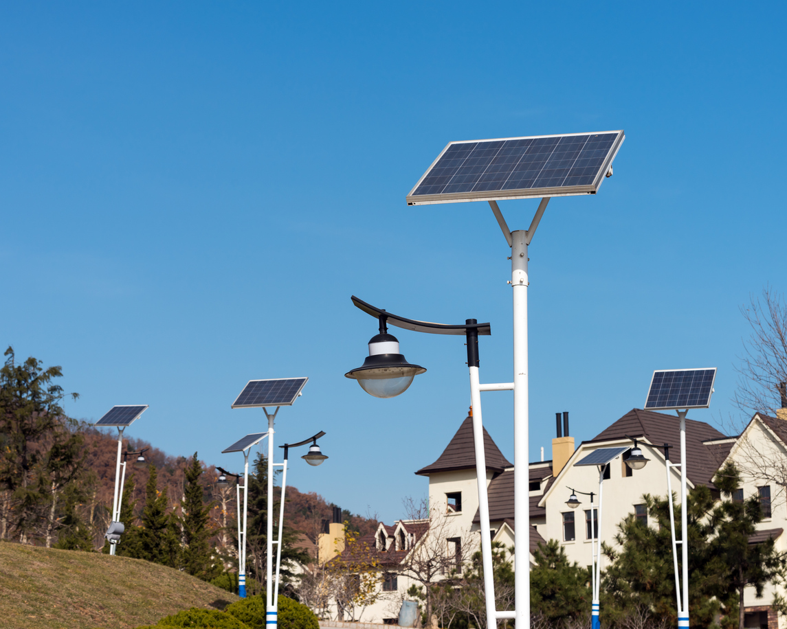 Alignement de candélabres solaires autonomes à panneau incliné en tête de mât dans un quartier résidentiel