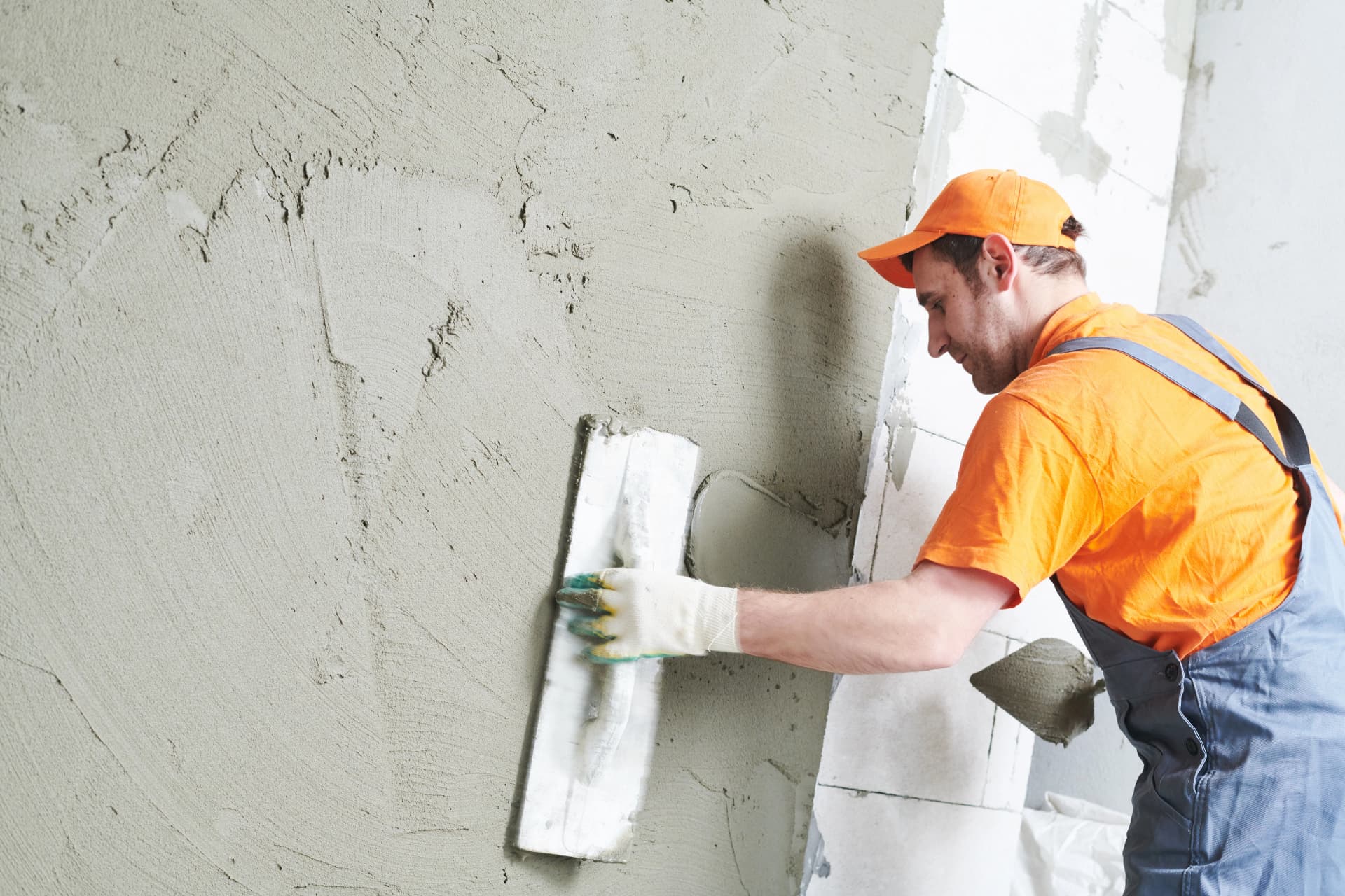 Façadier appliquant à la taloche l'enduit sur un mur isolé par l'extérieur