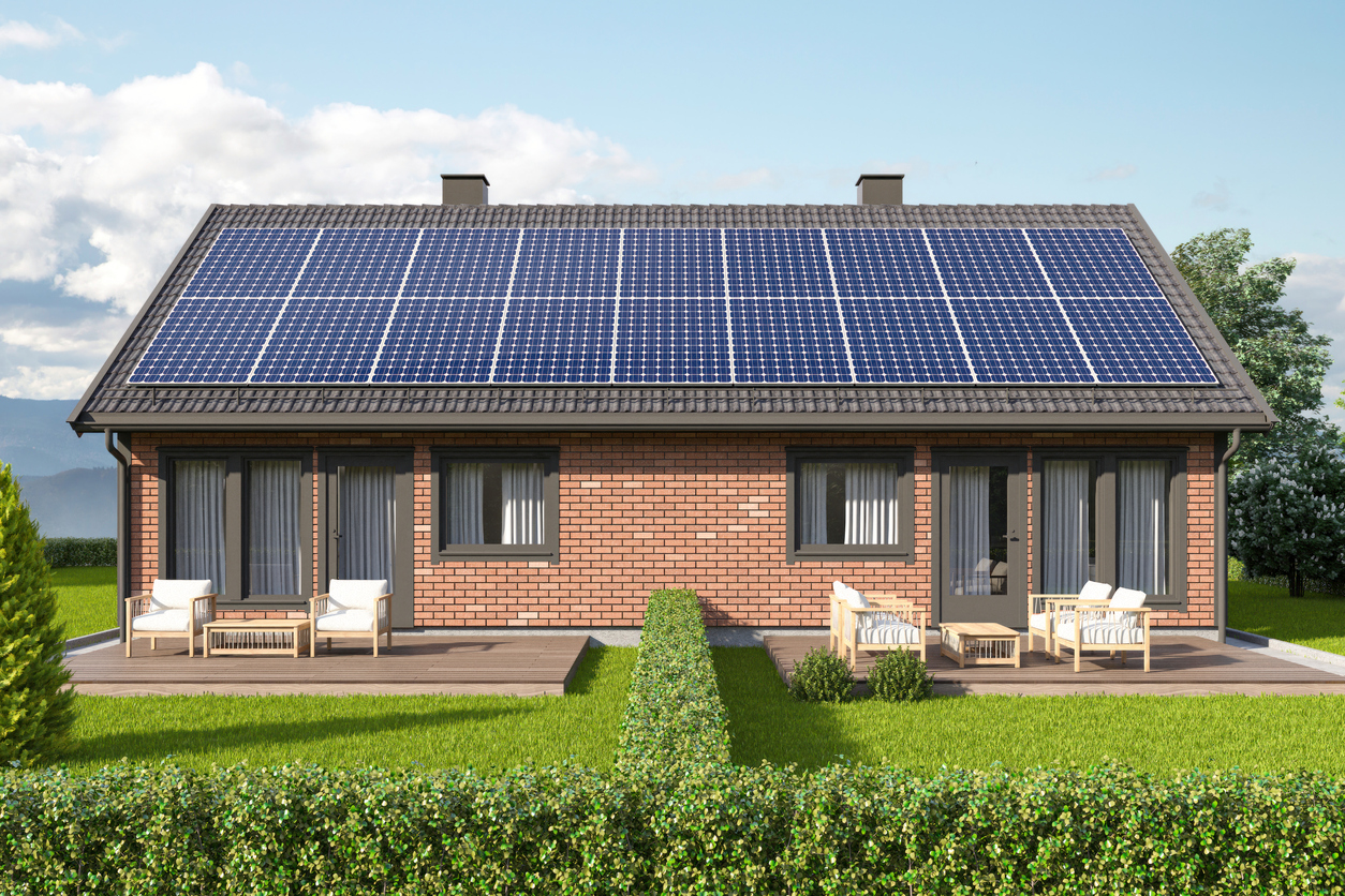Maison de plain-pied en brique dont la toiture est couverte de panneaux photovoltaïques
