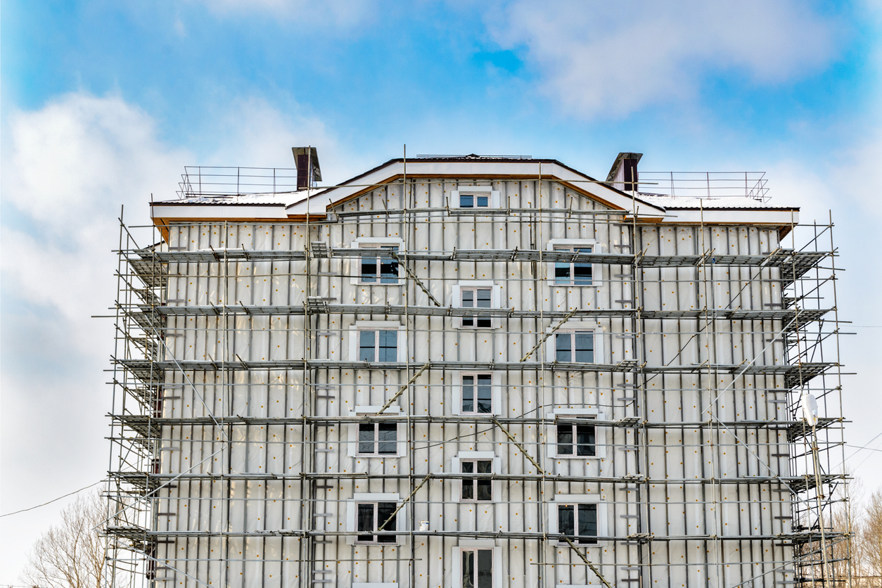 Bâtiment entièrement bâché sous échafaudage pendant son isolation par l'extérieur en hiver