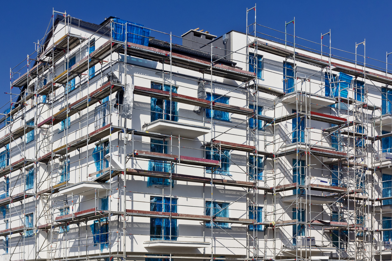 Grand bâtiment sous échafaudage complet pendant des travaux d'isolation thermique par l'extérieur