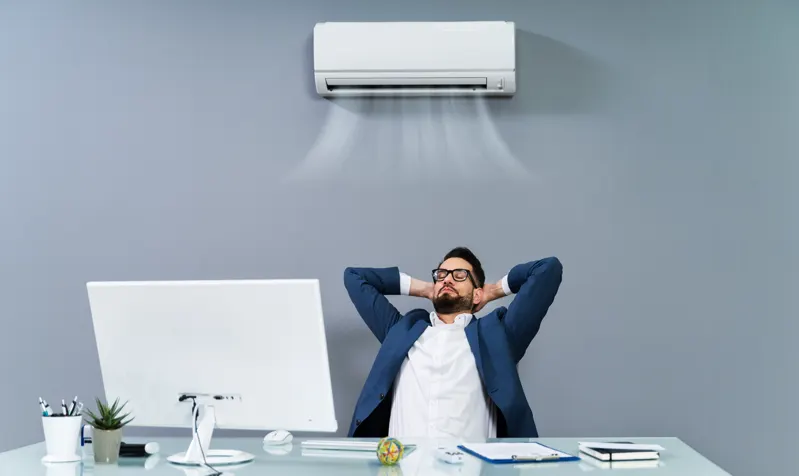 Occupant sous un split mural en appartement — climatisation réversible immeuble d’habitation dans le Grand Est