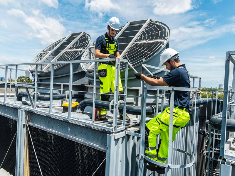 Techniciens intervenant sur les groupes froid en toiture — climatisation réversible immeuble d’habitation dans le Grand Est