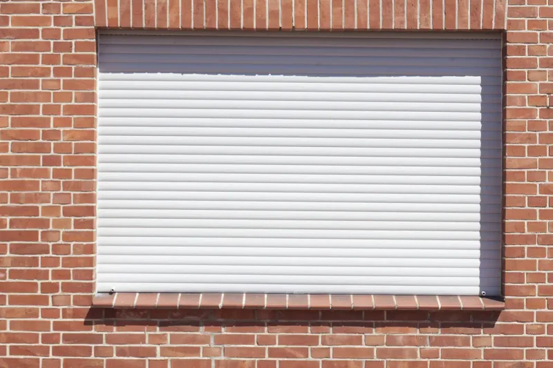 Volet roulant blanc sur façade en brique — France